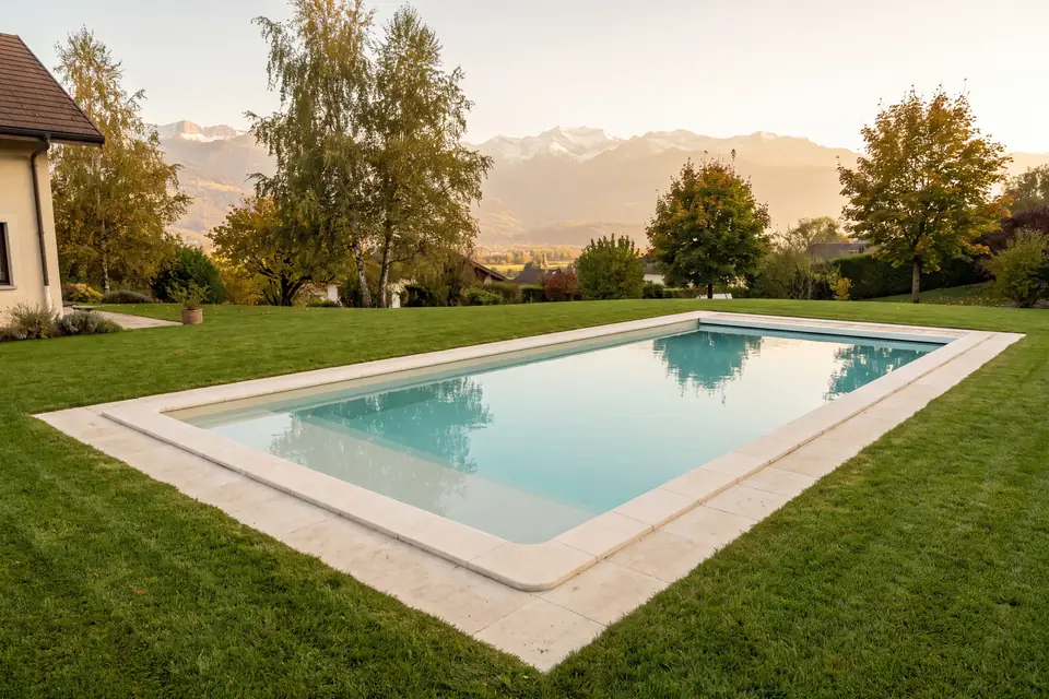 Renovated pool with pale stone coping set in a lawn, mountains in the distance